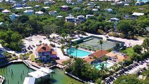 An aerial view of a resort with multiple buildings, a swimming pool, and a tennis court. - 4 Decks, Private Pool, Swim-up Tiki Bar, Hot Tub (North Captiva)
