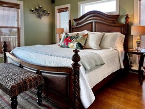 A neatly made bed with a quilted cover, a wooden headboard, and a bedside table with a lamp.