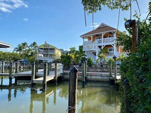 A waterfront property with a dock, a house with a balcony, and a sign that reads "Boats & Fun".