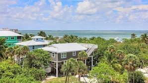 A coastal property with multiple buildings, including a house with a balcony and a separate structure with a flat roof. - 4 Decks, Private Pool, Swim-up Tiki Bar, Hot Tub (North Captiva)