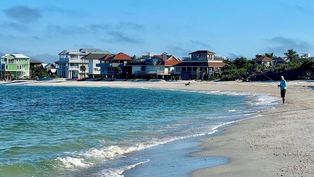 A beach with houses and a person fishing. - 4 Decks, Private Pool, Swim-up Tiki Bar, Hot Tub (North Captiva)