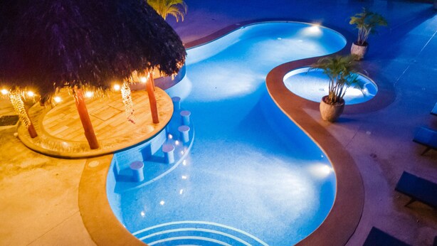 A swimming pool with a unique design, surrounded by a wooden deck and potted plants.