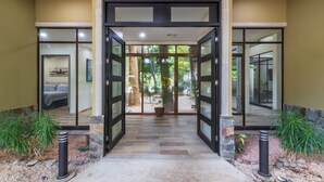 A hotel entrance with a glass door, a stone pathway, and potted plants.