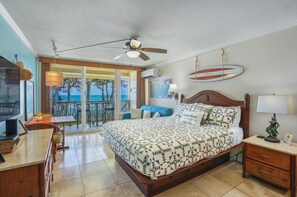 Ein Hotelzimmer mit Bett, Schreibtisch, Stuhl, Deckenventilator und Meerblick.