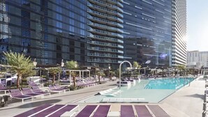 A rooftop pool area with lounge chairs and a swimming pool, surrounded by high-rise buildings.