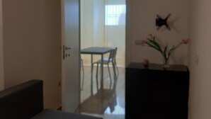 Ein Zimmer mit einem Bett, einem Schreibtisch und einem Stuhl. Eine Tür führt in einen weiteren Raum.