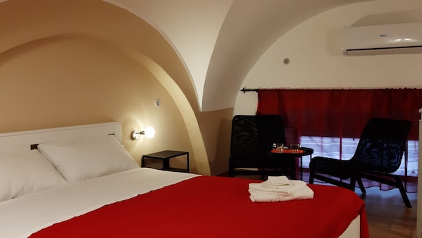 Ein Hotelzimmer mit einem großen Bett, einem kleinen Tisch, einem Stuhl und einem Fenster mit Vorhängen.