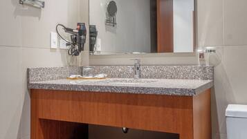 A bathroom with a granite countertop sink, a mirror, and a wooden vanity.