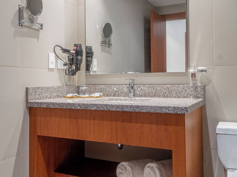 A bathroom with a granite countertop sink, a mirror, and a wooden vanity.
