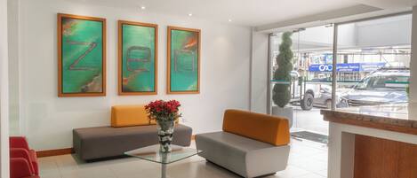 A reception area with a glass table, two sofas, and a vase of flowers.