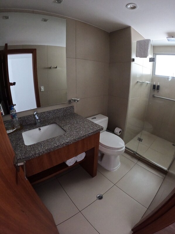 A bathroom with a double sink, toilet, and a glass shower enclosure. - Zen Hotel Quito (Quito)