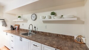 A kitchen with white cabinets, a granite countertop, a sink, and a clock on the wall. - Quiet, large private backyard, fully equipped, dreamy beds! 
Short or long term. (Halifax)