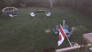 A backyard with a dining area, chairs, a flag, and a small table. - Quiet, large private backyard, fully equipped, dreamy beds! 
Short or long term. (Halifax)