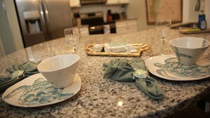 A kitchen counter with two plates, two bowls, and two wine glasses. - Luxury Condo at Village Pier, King Bed,Full Kitchen, Polaris Ranger for Rent (St. Simons Island)