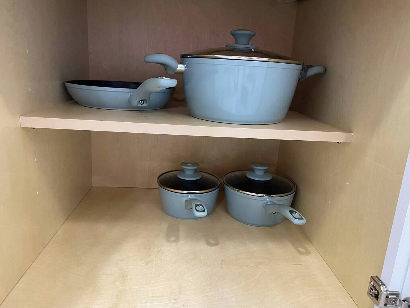 Um armário de cozinha com três panelas nas prateleiras.