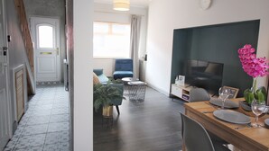 En moderne stue med spiseplads, et fjernsyn og en trappe til et andet rum.