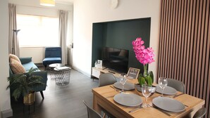 En moderne stue med spiseplads, et fladskærms-tv og en potteplante.