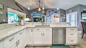 Une cuisine moderne avec des meubles blancs, un grand îlot central et un ventilateur de plafond.