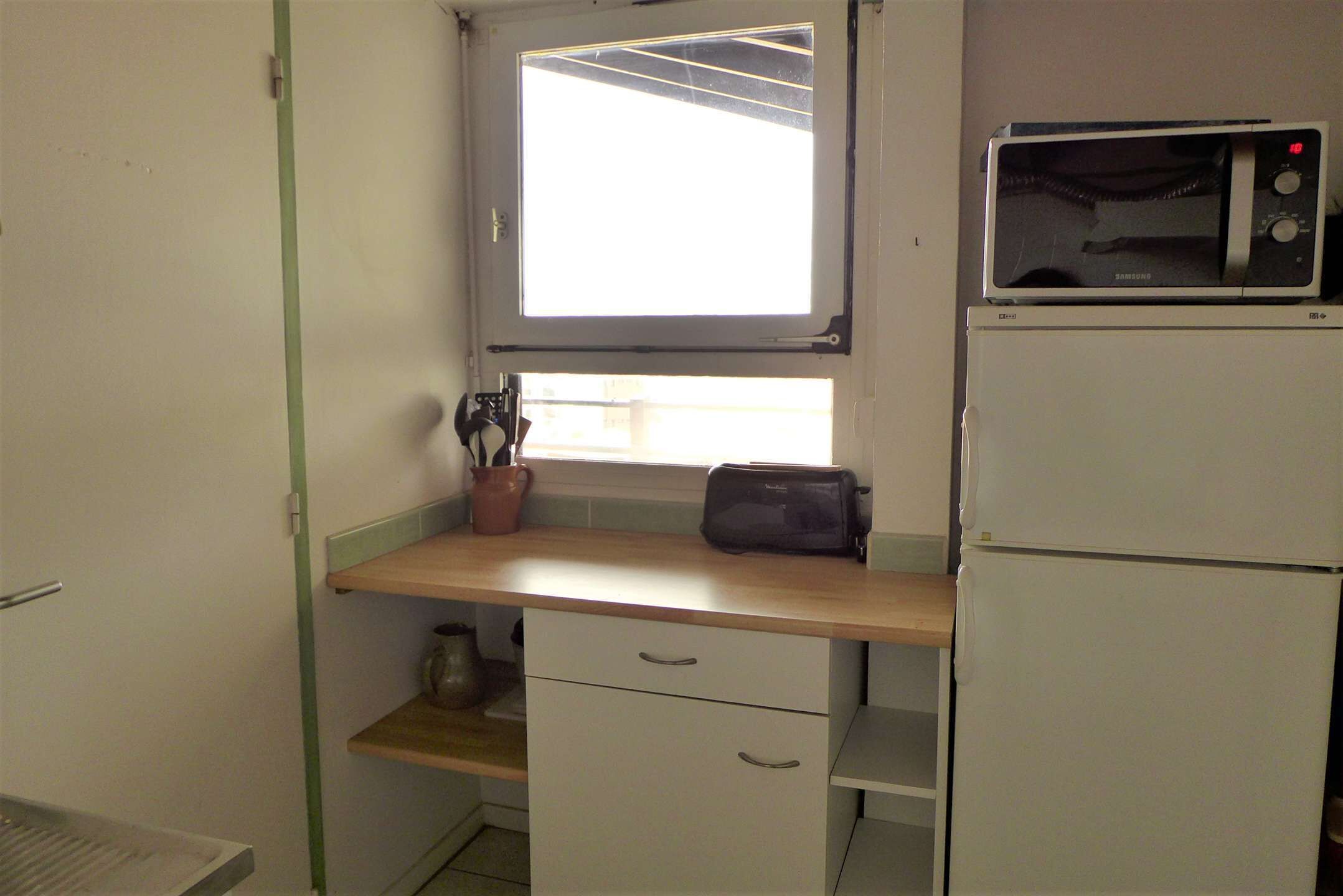 A compact kitchen with a window, a microwave, a toaster, and a sink.