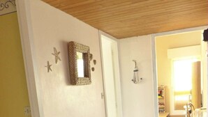 A room with wooden flooring, a white door, a metal rack, and a mirror on the wall.