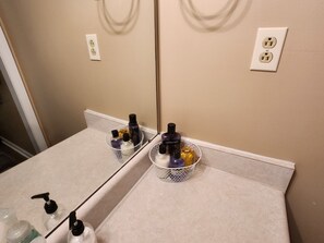 A bathroom with a mirror, two electrical outlets, and two baskets containing toiletries. - Country Home in Oak Grove (Oak Grove)