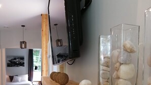 Uma sala de estar moderna com uma mesa de centro de madeira, uma televisão de tela plana na parede e uma vitrine de vidro com pedras empilhadas.