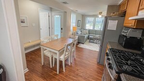 Una cocina con una mesa de comedor, sillas, un refrigerador y una estufa.
