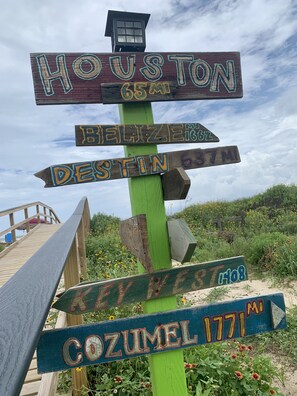 A wooden signpost with directional signs to Houston, Belize, Destin, and Cozumel. - *Blue- tiful Views*  (Surfside Beach)
