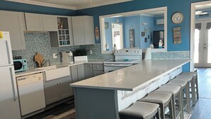 A kitchen with a central island, bar stools, a ceiling fan, and a microwave. - *Blue- tiful Views*  (Surfside Beach)