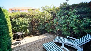 A patio with a grill, two striped lounge chairs, and a table. - Residence with swimming pool and private parking space! (LA SEYNE SUR MER)