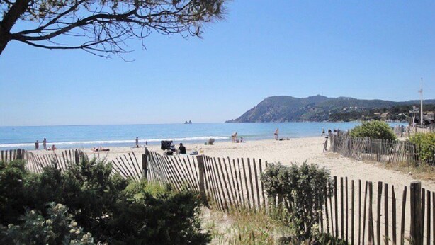A beach with a wooden fence, people sunbathing, and a clear blue sky. - Residence with swimming pool and private parking space! (LA SEYNE SUR MER)