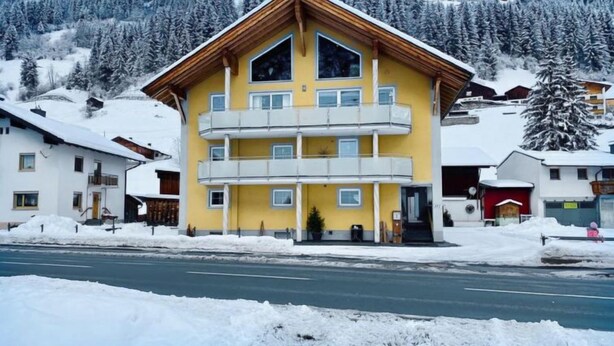 A multi-story yellow building with balconies, surrounded by snow-covered trees and a mountain in the background. - Sesselebenerhof by Interhome (See)