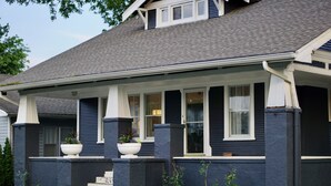 A two-story house with a covered porch, a front entrance with steps, and a small front yard.