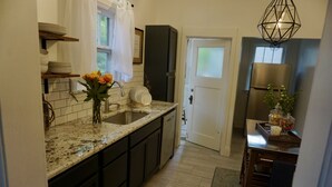 A kitchen with a granite countertop, dark cabinets, a sink, and a refrigerator.
