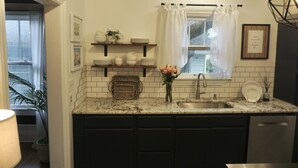 A kitchen with dark cabinets, a granite countertop, a sink, and a window with a curtain.