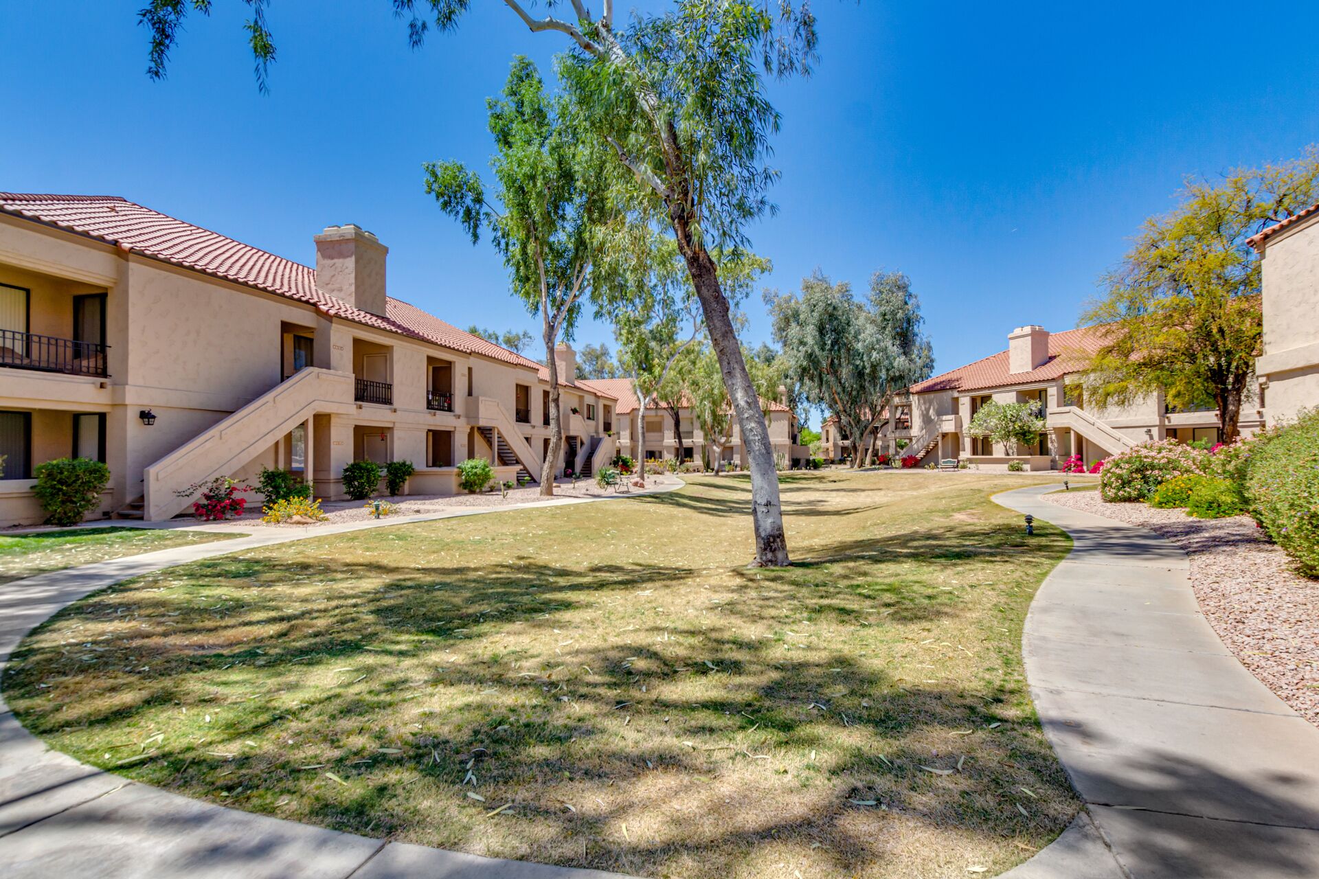 A residential complex with multiple-story buildings, a central lawn, and a curved pathway.
