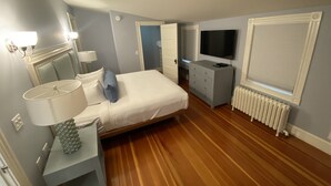 Un dormitorio con cama, cómoda, televisión y radiador.