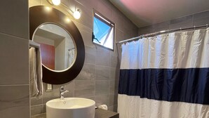 Um banheiro moderno com espelho redondo, pia branca, vaso sanitário e cortina de chuveiro.