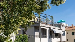 A two-story building with balconies, a terrace, and a blue umbrella. - Sleeps 8, Pet Friendly, Garden & Roof Terrace (Split)