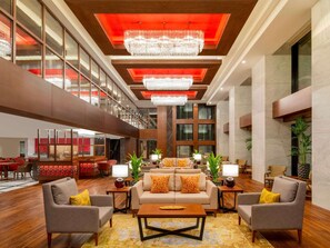 A spacious lobby with a high ceiling, large windows, and modern chandeliers.