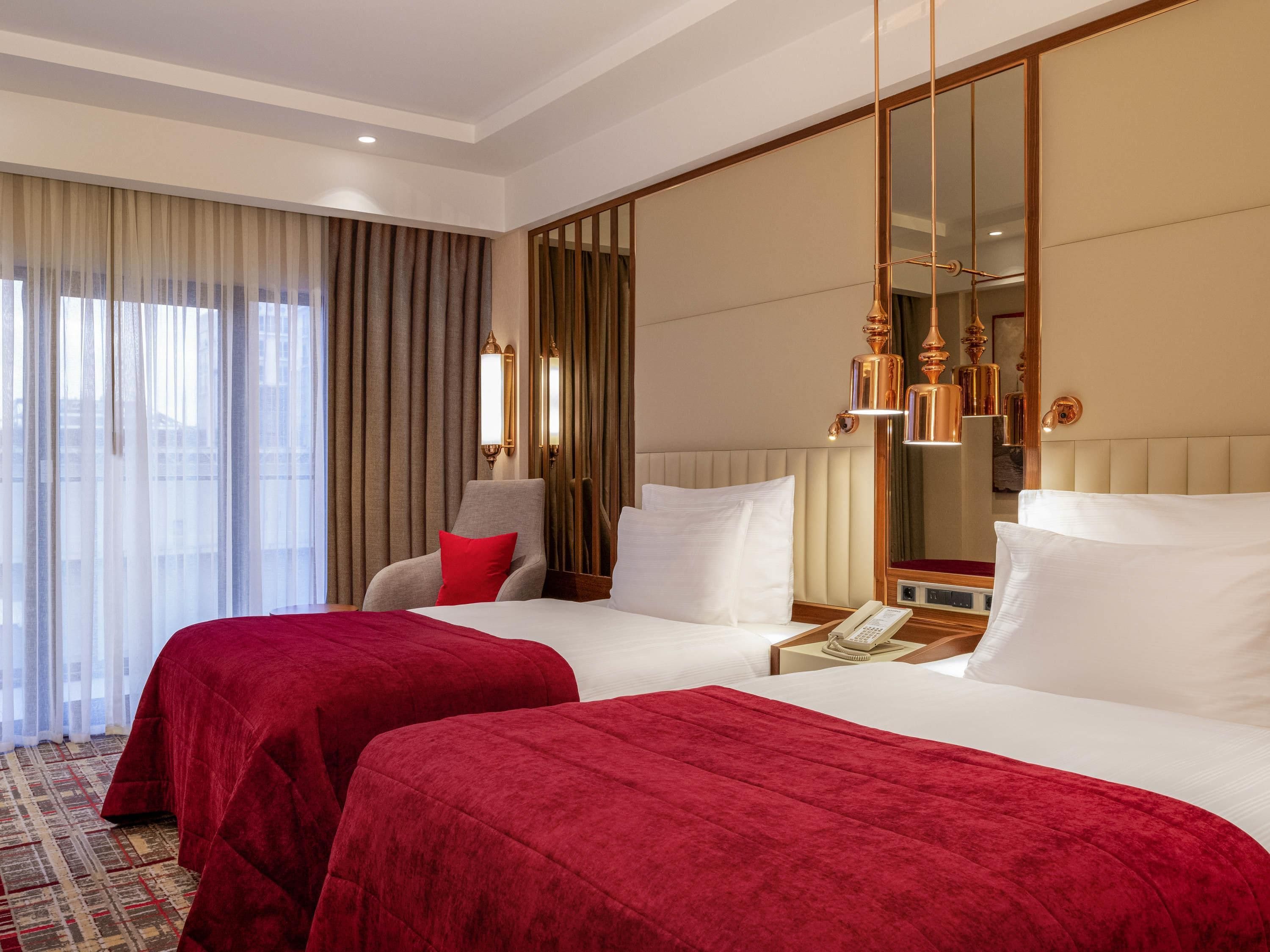 Habitación de hotel con dos camas, un espejo grande, una silla y un teléfono en la mesita de noche.