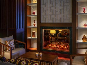 A cozy lounge area with a fireplace, seating, and decorative shelves. - Mövenpick Hotel Istanbul Asia Airport (Istanbul)