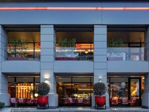 A modern building with a glass facade, outdoor seating, and potted plants. - Mövenpick Hotel Istanbul Asia Airport (Istanbul)