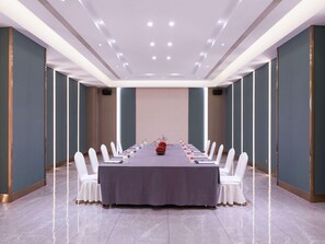 A conference room with a long table, white chairs, and a grey tablecloth. - Mercure Shijiazhuang People Square (Shijiazhuang)
