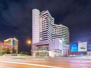 A modern hotel with a curved facade, multiple floors, and illuminated signage. - Mercure Shijiazhuang People Square (Shijiazhuang)