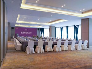 A conference room with a long table set for meetings, featuring a purple wall with a welcome sign, and a carpeted floor. - Mercure Shijiazhuang People Square (Shijiazhuang)