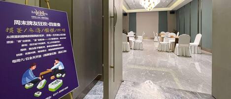 Un hall de hotel con una zona de recepción, una araña y un área de descanso con mesas y sillas.