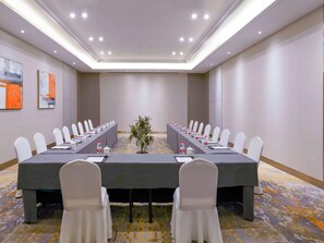 A conference room with a long table, white chairs, and a plant in the center. - Mercure Shijiazhuang People Square (Shijiazhuang)
