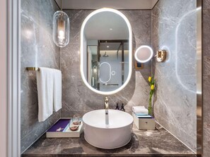 A modern bathroom with a round mirror, a sink, and a towel rack.
