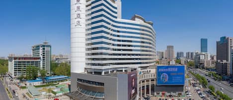 A modern hotel with a curved facade, multiple floors, and a prominent vertical sign.